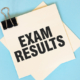900-text-exam-results-on-sticky-notes-with-copy-space-and-paper-clip-isolated-on-red-background-finance-and-economics-concept