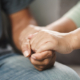 900_medium-female-friend-or-family-sitting-and-hold-hands-during-cheer-up-to-mental-depress-man-psychologist-provides-mental-aid-to-patient-ptsd-mental-health-concept
