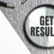 900-get-results-symbol-on-magnifier-and-pen-on-wooden-background